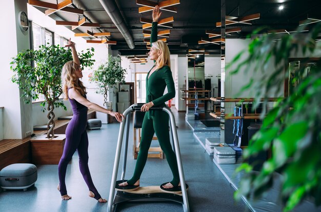 Mulher idosa fazendo reabilitação física e pilates com seu treinador no centro esportivo