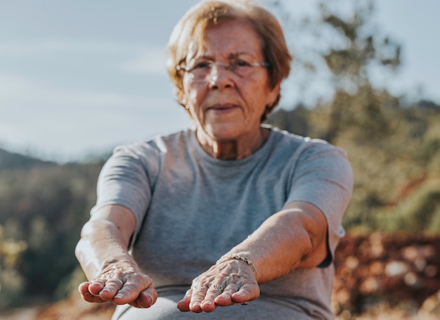 Foto mulher idosa fazendo seus trechos no parque com foco seletivo nos dedos