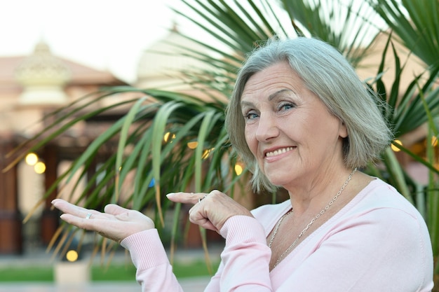 Mulher idosa feliz apontando para um jardim tropical ao ar livre