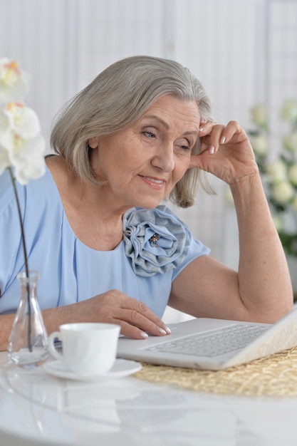 Mulher idosa feliz com laptop em casa