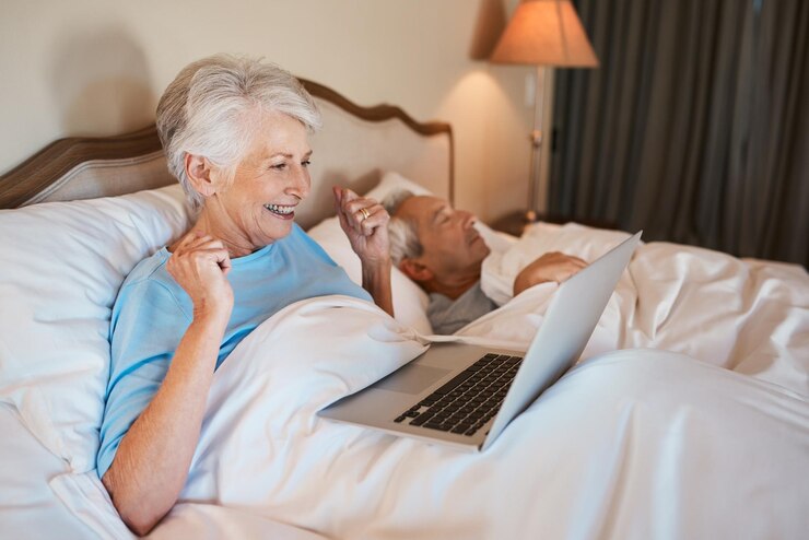 Foto mulher idosa feliz e laptop com surpresa na cama para boas notícias ganhando ou promoção em casa pessoa feminina idosa ou vencedora com sorriso no computador para a vitória negócio de loteria ou prêmio no quarto