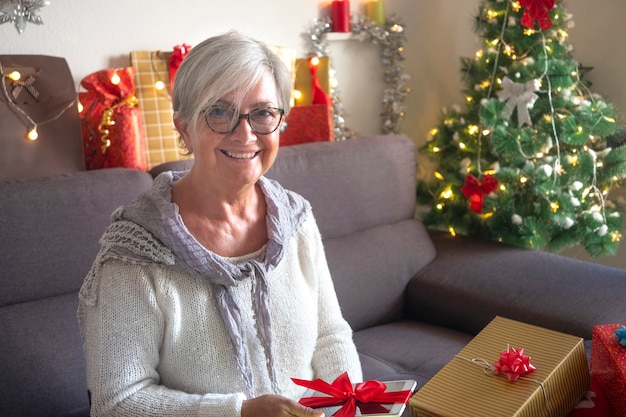 Mulher idosa feliz recebe um novo tablet como presente de Natal. Um idoso moderno, tecnológico e social, aproveitando as férias de Natal