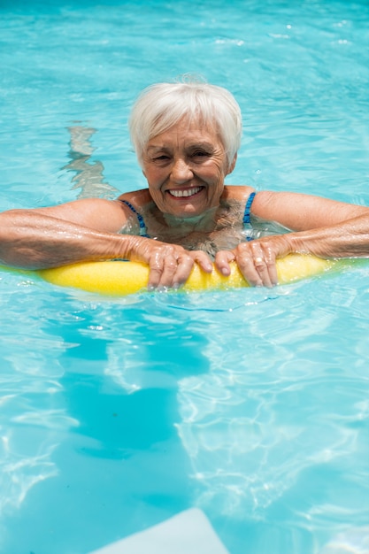Mulher idosa nadando com tubo inflável na piscina