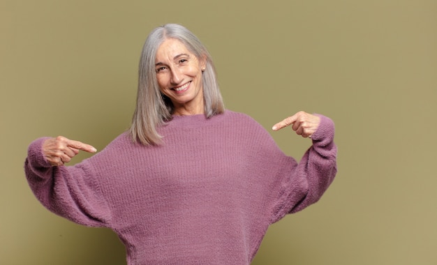 Mulher idosa parecendo orgulhosa, arrogante, feliz, surpresa e satisfeita, apontando para si mesma, sentindo-se uma vencedora