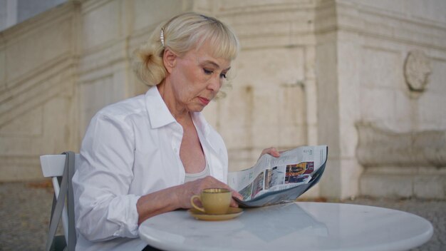 Foto mulher idosa procurando revista no terraço do restaurante perto de mulher idosa lendo