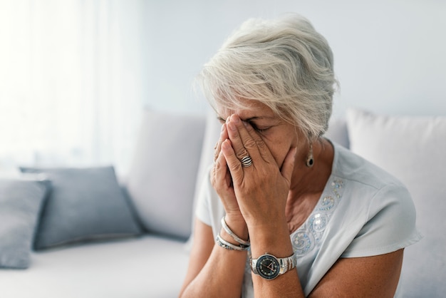 Mulher idosa que sofre de dor de cabeça em casa