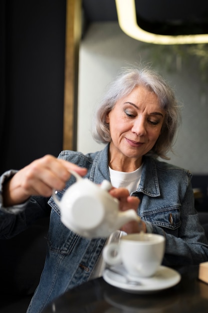 Foto mulher idosa reabastecendo sua xícara de café em um café