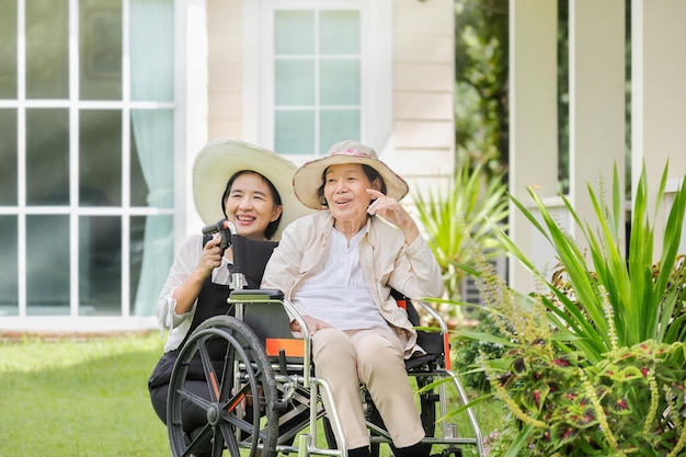 Mulher idosa relaxando em cadeira de rodas no quintal com a filha
