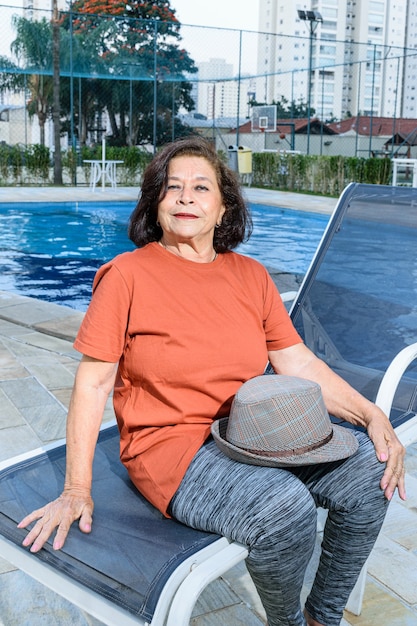 Mulher idosa sentada à beira da piscina