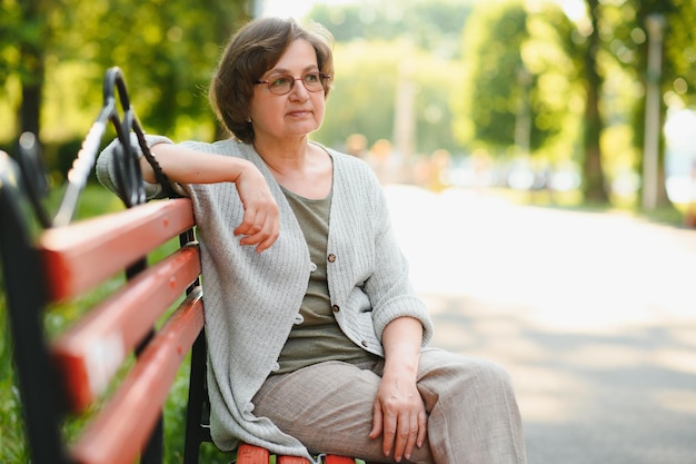 Mulher idosa sentada e relaxando em um banco ao ar livre no parque