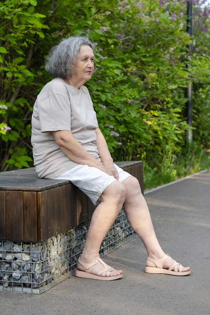 Mulher idosa sentada em um banco de parque olhando para frente