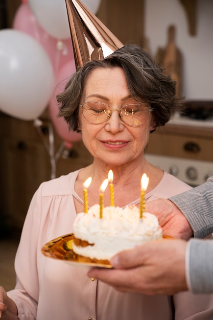Foto mulher idosa soprando velas e se divertindo na festa