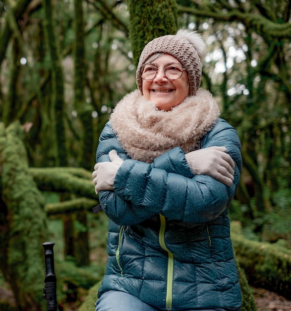 mulher idosa sorridente caminhando no parque nacional de Garajonay em La Gomera abraçando-se sentindo frio
