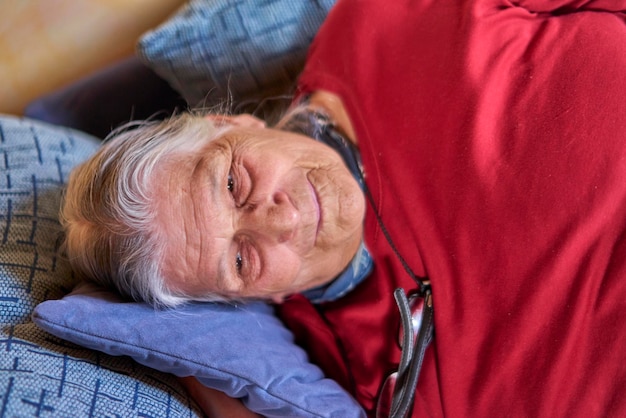 Mulher idosa sorridente deitada no sofá em casa