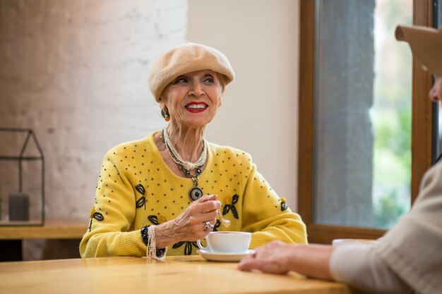 Mulher idosa sorridente e xícara