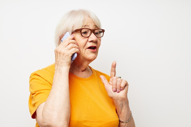 Mulher idosa sorridente em uma camiseta amarela posando comunicação por telefone closeup emoções