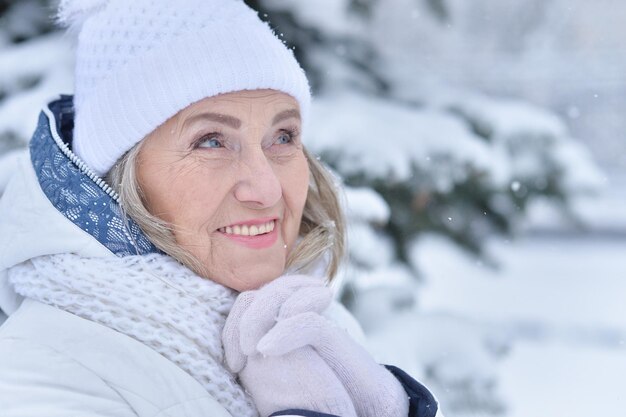 Mulher idosa sorrindo e se regozijando no inverno nevado