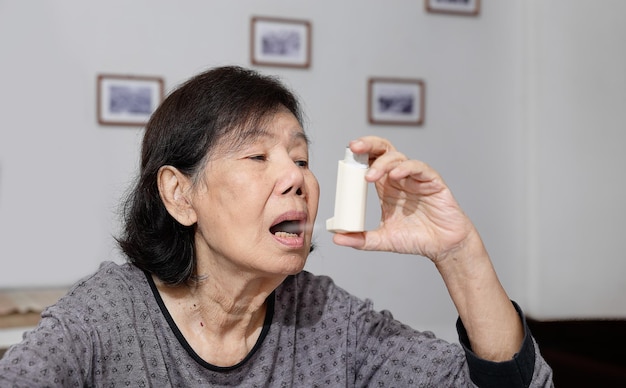Mulher idosa sufocando e segurando um spray para asma
