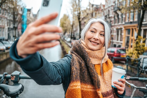 Foto mulher idosa toma café da manhã em amsterdã e tira uma selfie