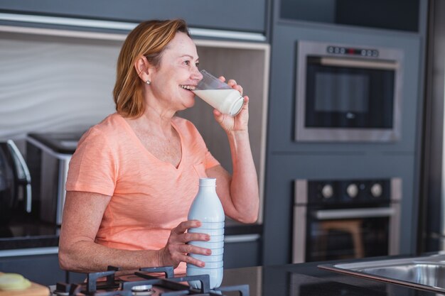 Mulher idosa tomando um copo de leite pela manhã.