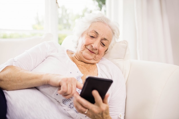 Mulher idosa, usando, dela, smartphone, mentindo sofá