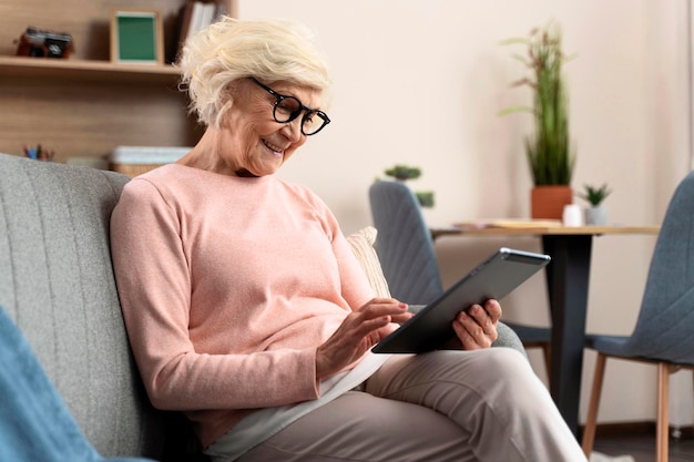 Mulher idosa usando tablet digital enquanto está sentada no sofá em casa Tecnologias e conceito de pessoas idosas Foto Premium