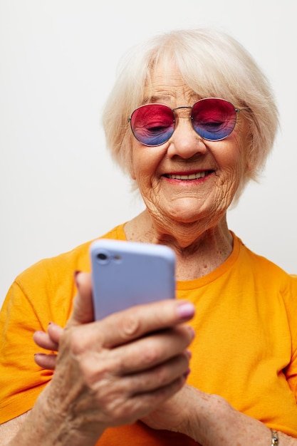 Mulher idosa usando telefone móvel contra fundo branco