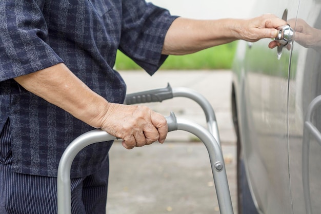 Mulher idosa usando um andador no estacionamento