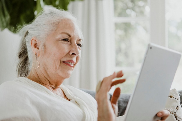 Mulher idosa usando um tablet no sofá