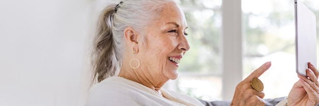 Mulher idosa usando um tablet no sofá