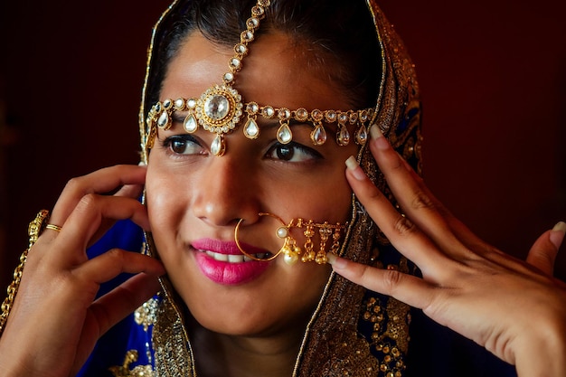 Mulher iluminando diyas com piercing no nariz nuth nath e a teca dourada com sari de moda tradicional