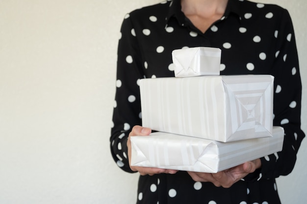 Mulher incidental segurando presentes de natal, foco seletivo, luz de fundo e espaço de cópia.