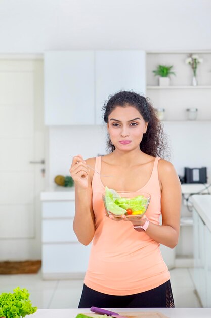 Mulher indiana comendo uma tigela de salada saborosa em casa