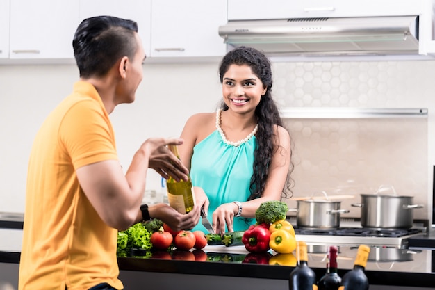 Mulher indiana e homem na cozinha com vinho tinto