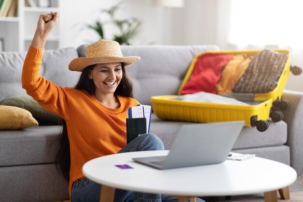 Foto mulher indiana feliz planejando férias sentada na frente do laptop