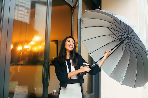 mulher indiana feliz rindo com um telefone e um guarda-chuva