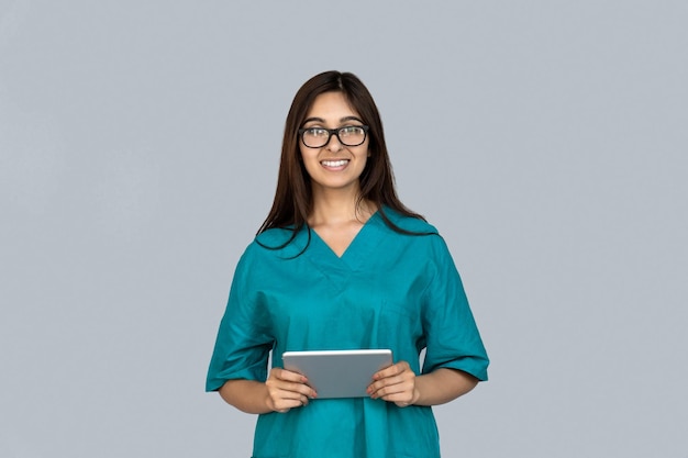 Mulher indiana jovem e adulta feliz em uniforme de médico segurando um tablet.