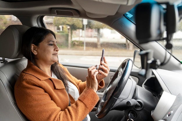 Mulher indiana madura ocupada segurando telefone celular dirigindo carro Transporte distraído dirigindo