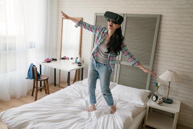 Mulher infantil asiática usando seu dispositivo VR e abre os braços como se fosse um pássaro voando no céu.