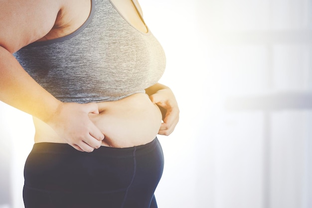 Mulher infeliz beliscando sua barriga gorda em casa