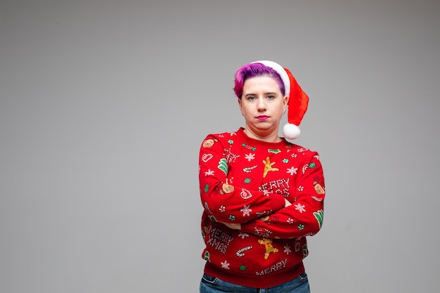 Mulher infeliz com um chapéu pendurado na cabeça, com as mãos cruzadas e sem clima de natal. copie o espaço