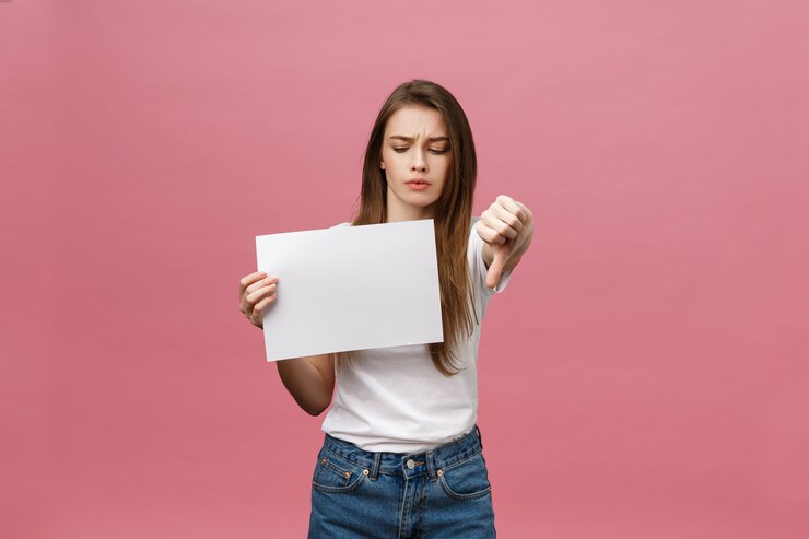 Foto mulher infeliz fazendo gesto de polegar para baixo com papel em branco