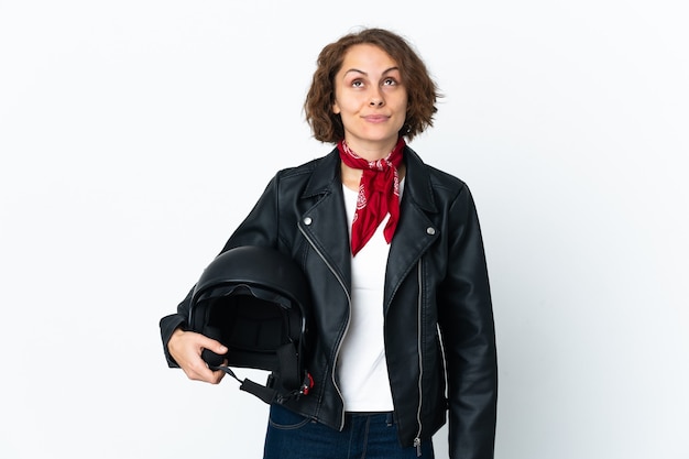 Mulher inglesa segurando um capacete de motociclista isolado no espaço em branco e olhando para cima