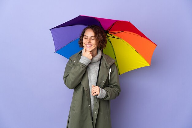 Mulher inglesa segurando um guarda-chuva isolado no espaço roxo, olhando para o lado e sorrindo