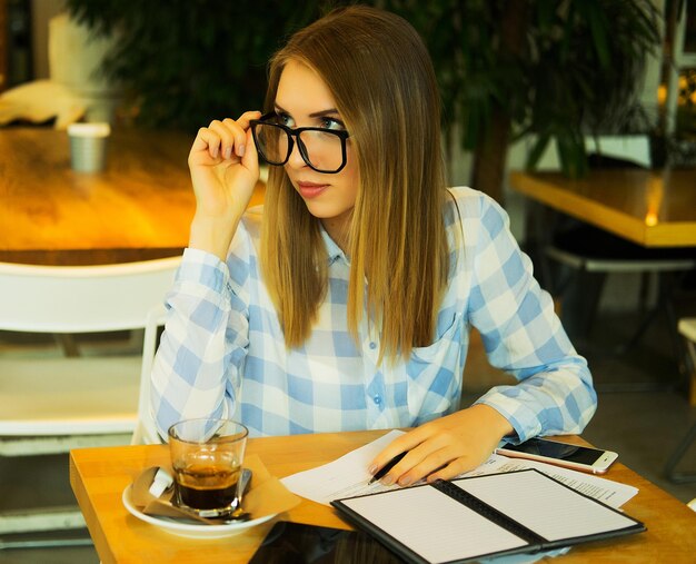 Mulher inteligente anotando suas ideias e bebendo café no café