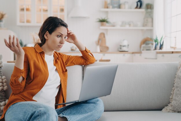 Mulher intrigada olhando para a tela do laptop tem problemas com vírus de computador ou má conexão com a internet