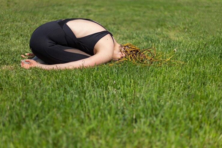 Foto mulher iogue com dreadlocks fazendo pose de ioga deitada de bruços