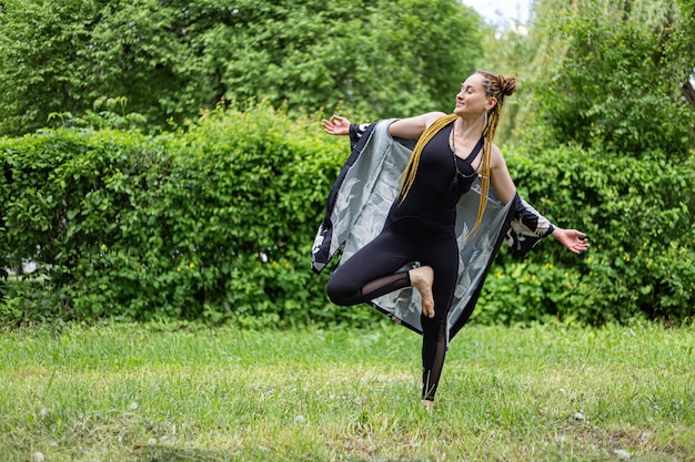 Mulher iogue com dreadlocks praticando pose de árvore Vrikshasana de ioga