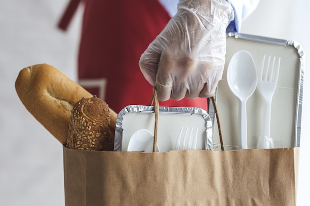 Mulher irreconhecível com sacos de comida para viagem.