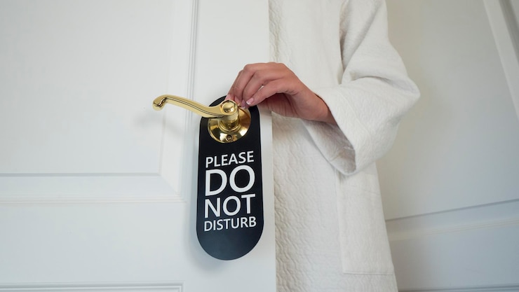 Foto mulher irreconhecível com um casaco branco pendura um letreiro na porta não perturbe